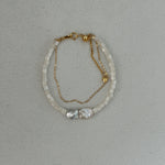 A two-layered pearl bead bracelet with gold plating on a silver chain, featuring a single large pearl at the center.