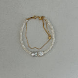 A two-layered pearl bead bracelet with gold plating on a silver chain, featuring a single large pearl at the center.