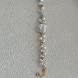 A bracelet with a combination of round pearls and gold-colored accents on a pale background.