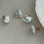 A set of baroque pearl earrings with 18K gold plating on brass, displayed on a white surface next to a plate.