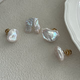 A set of baroque pearl earrings with 18K gold plating on brass, displayed on a white surface next to a plate.