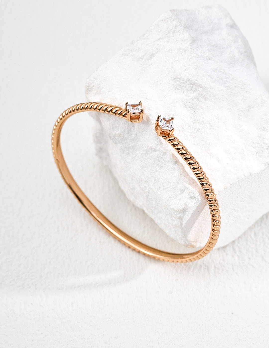 Rose gold bracelet on a textured white surface