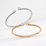 Two bracelets, one silver and one rose gold, on a light gray background