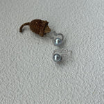 Small toy hedgehog next to a pair of silver earrings on a textured white surface