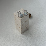 Pair of earrings on a small concrete block against a light background