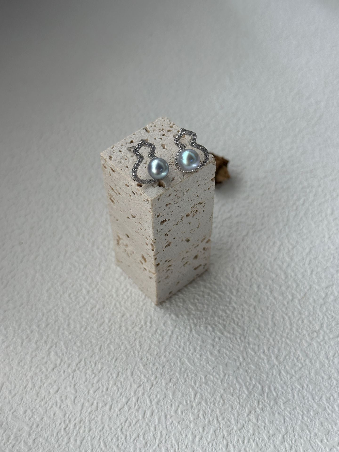 Pair of earrings on a small concrete block against a light background