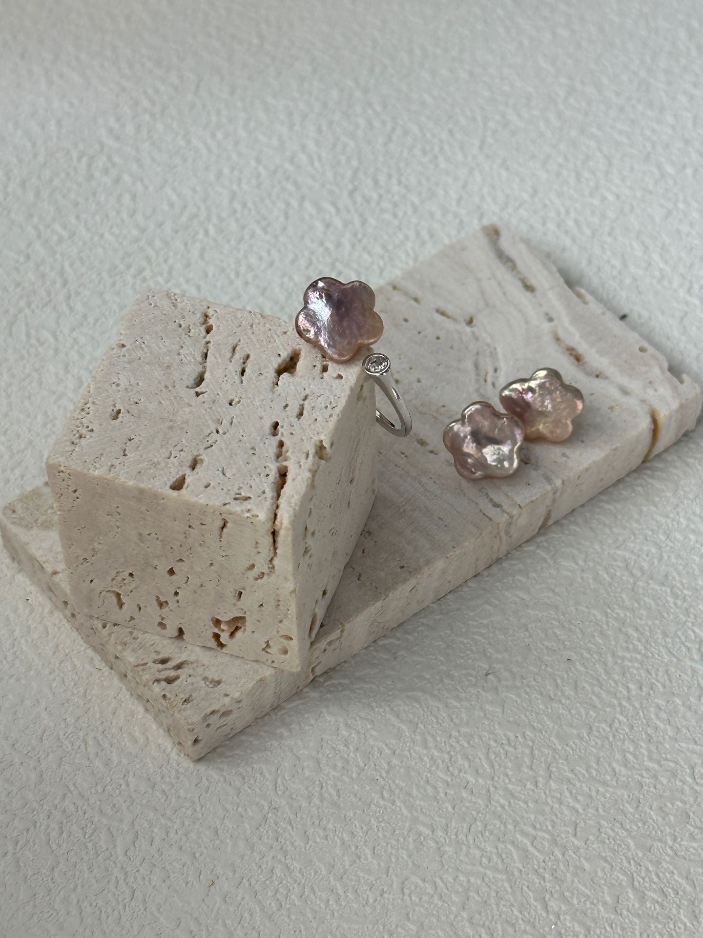 Pair of pink flower-shaped earrings on a stone surface