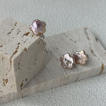 Pair of pink pearl earrings on a textured stone surface