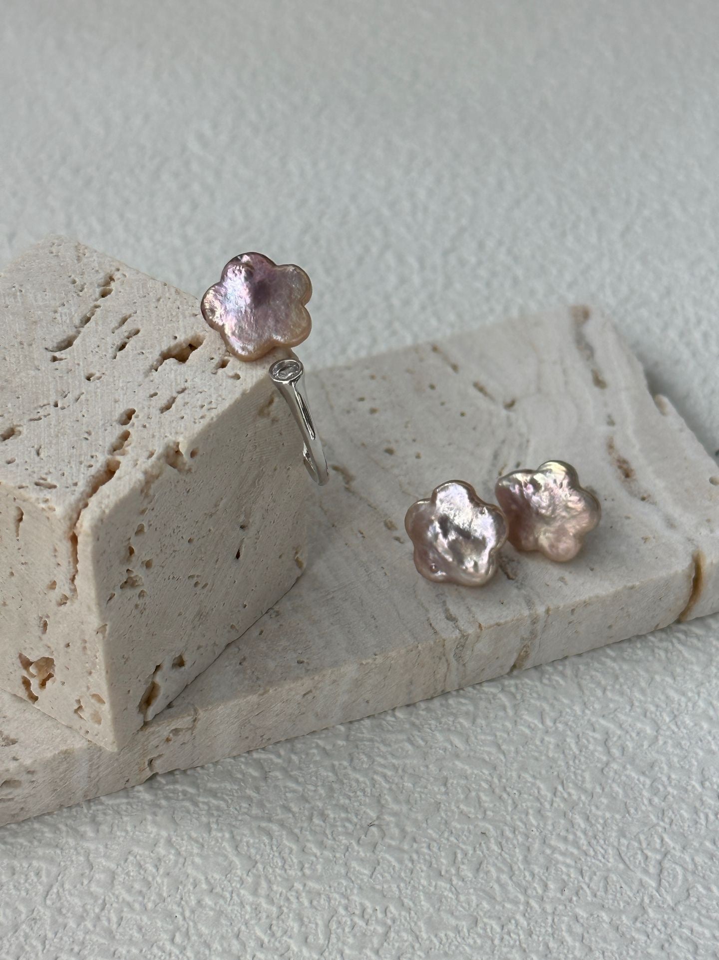 Pair of pink pearl earrings on a textured stone surface
