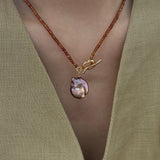 Necklace with a pendant on a green garment