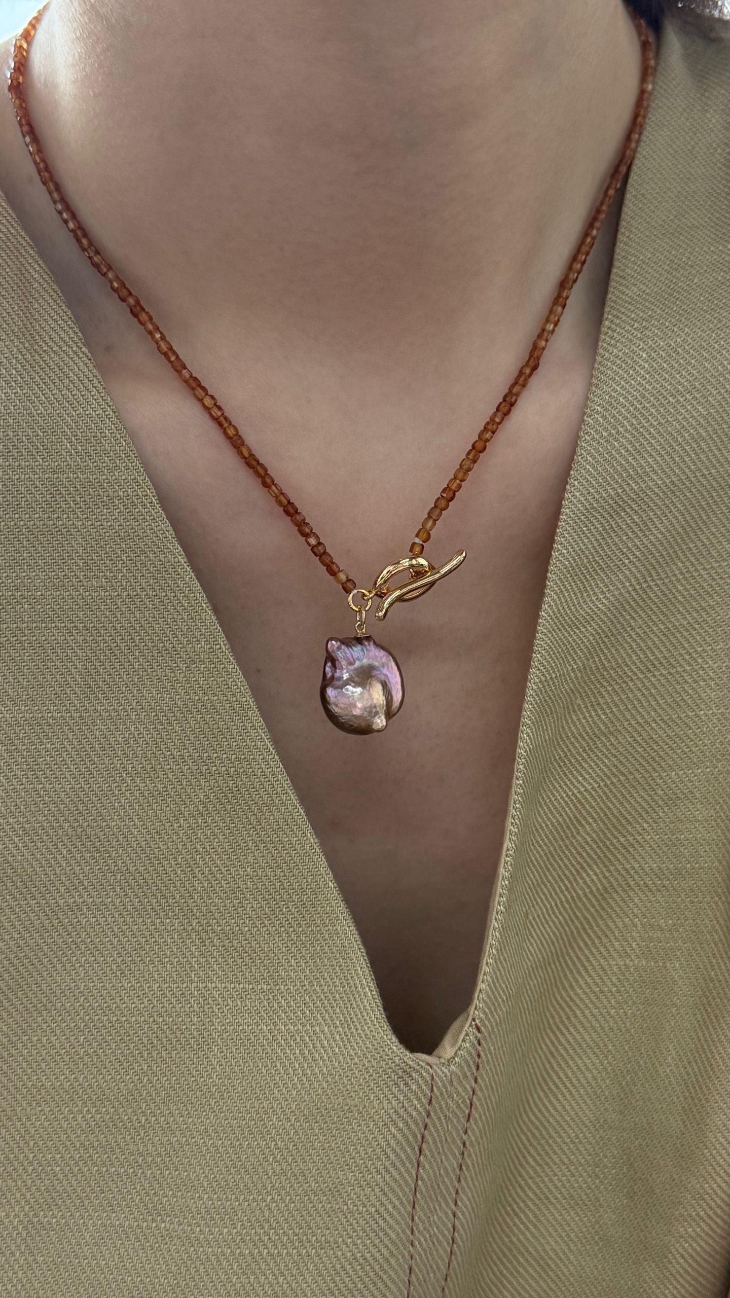 Necklace with a pendant on a green garment