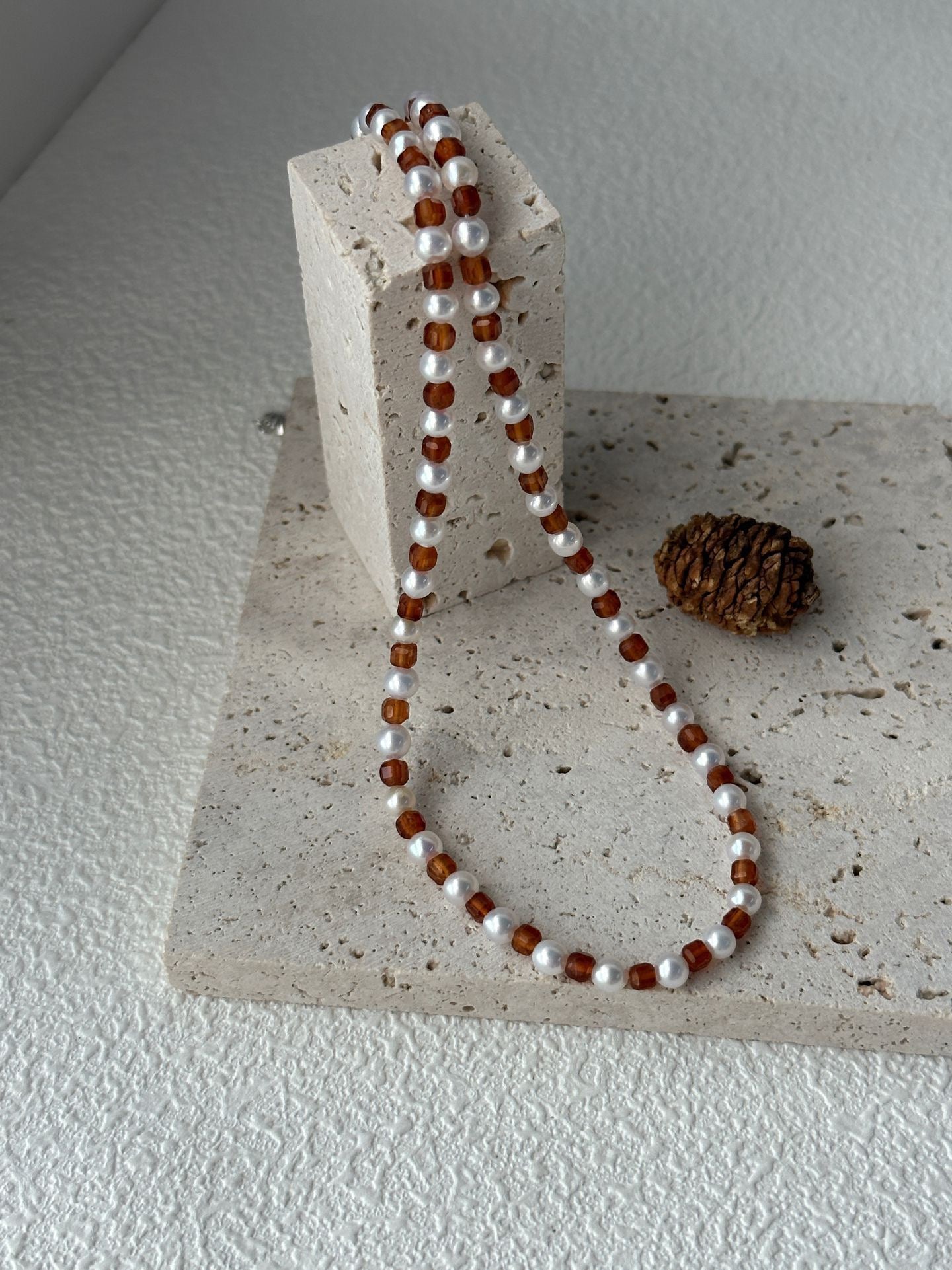 Necklace with alternating brown and white beads on a textured stone surface.