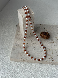 Necklace with alternating brown and white beads on a textured stone surface.