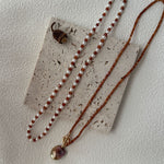 Necklace with red and white beads and a pendant on a textured surface