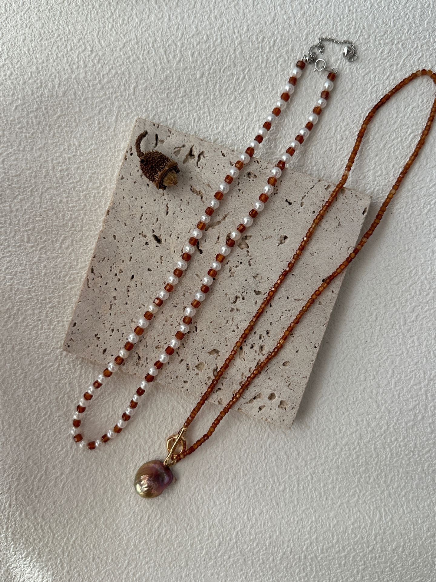 Necklace with red and white beads and a pendant on a textured surface