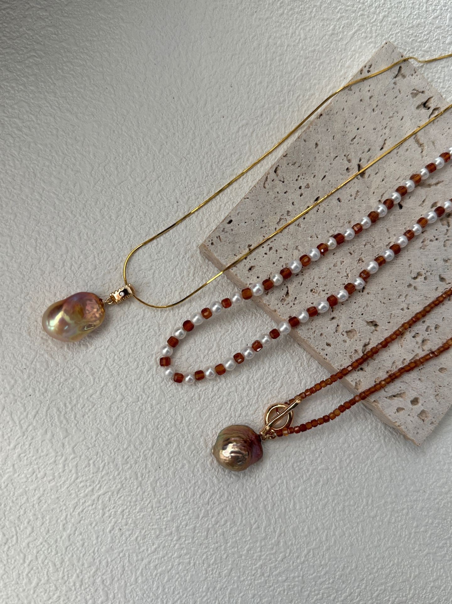 Three necklaces with beads on a textured surface