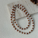 Necklace with alternating brown and white beads on a light surface.