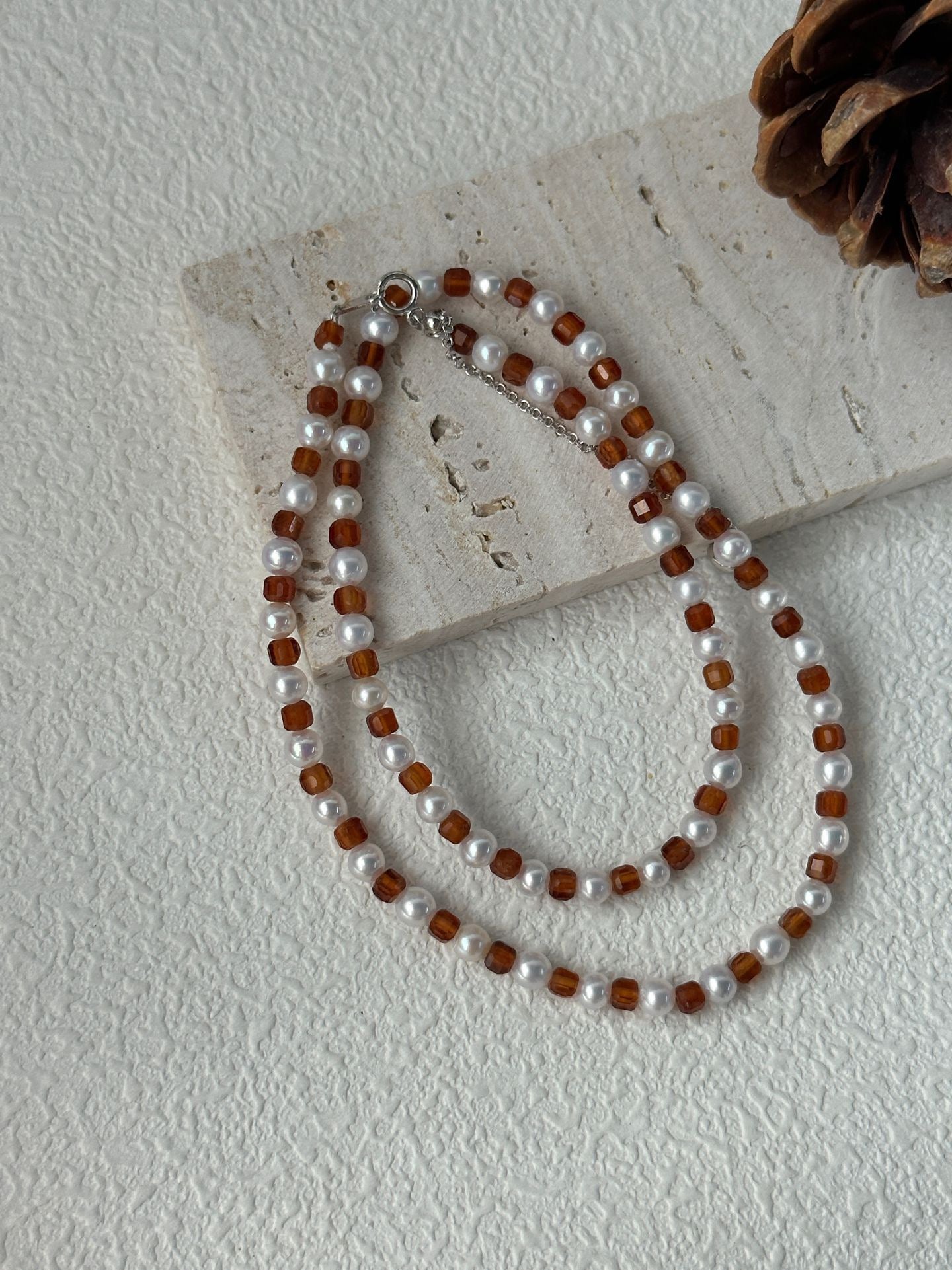 Necklace with alternating brown and white beads on a light surface.