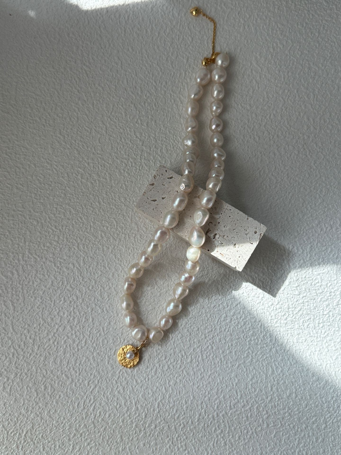 Pearl necklace with a gold clasp on a light gray background