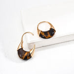 Pair of tortoiseshell hoop earrings on a white surface