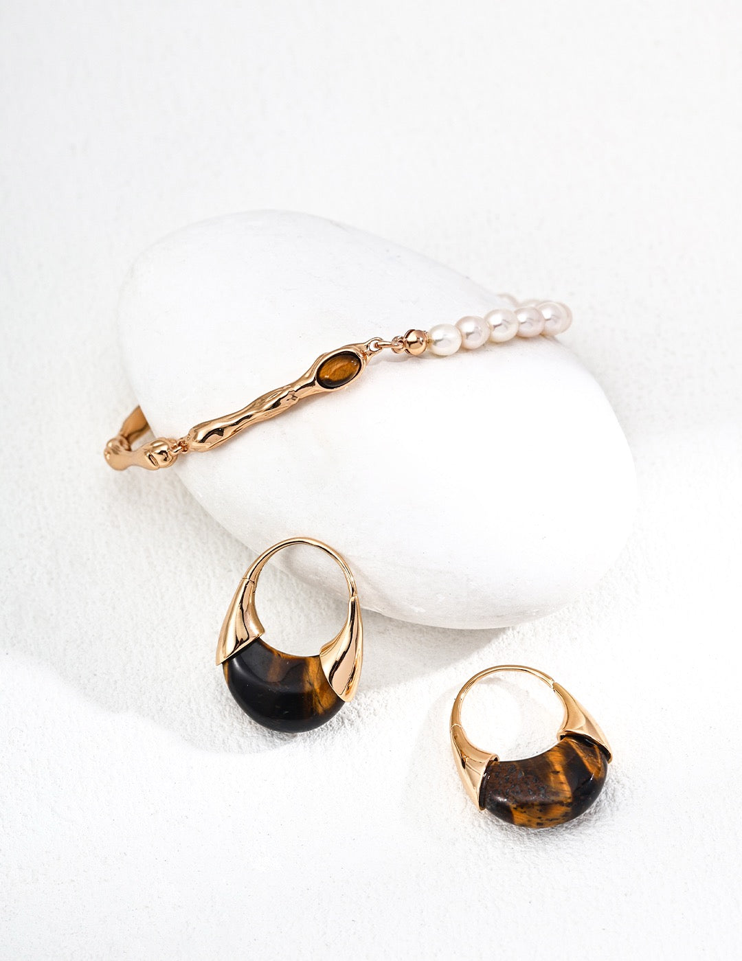 Gold jewelry set with tiger eye stones on a white background