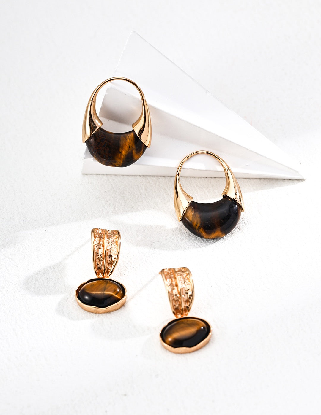 Set of gold and black earrings on a white surface