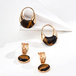 Set of gold and black earrings on a white surface