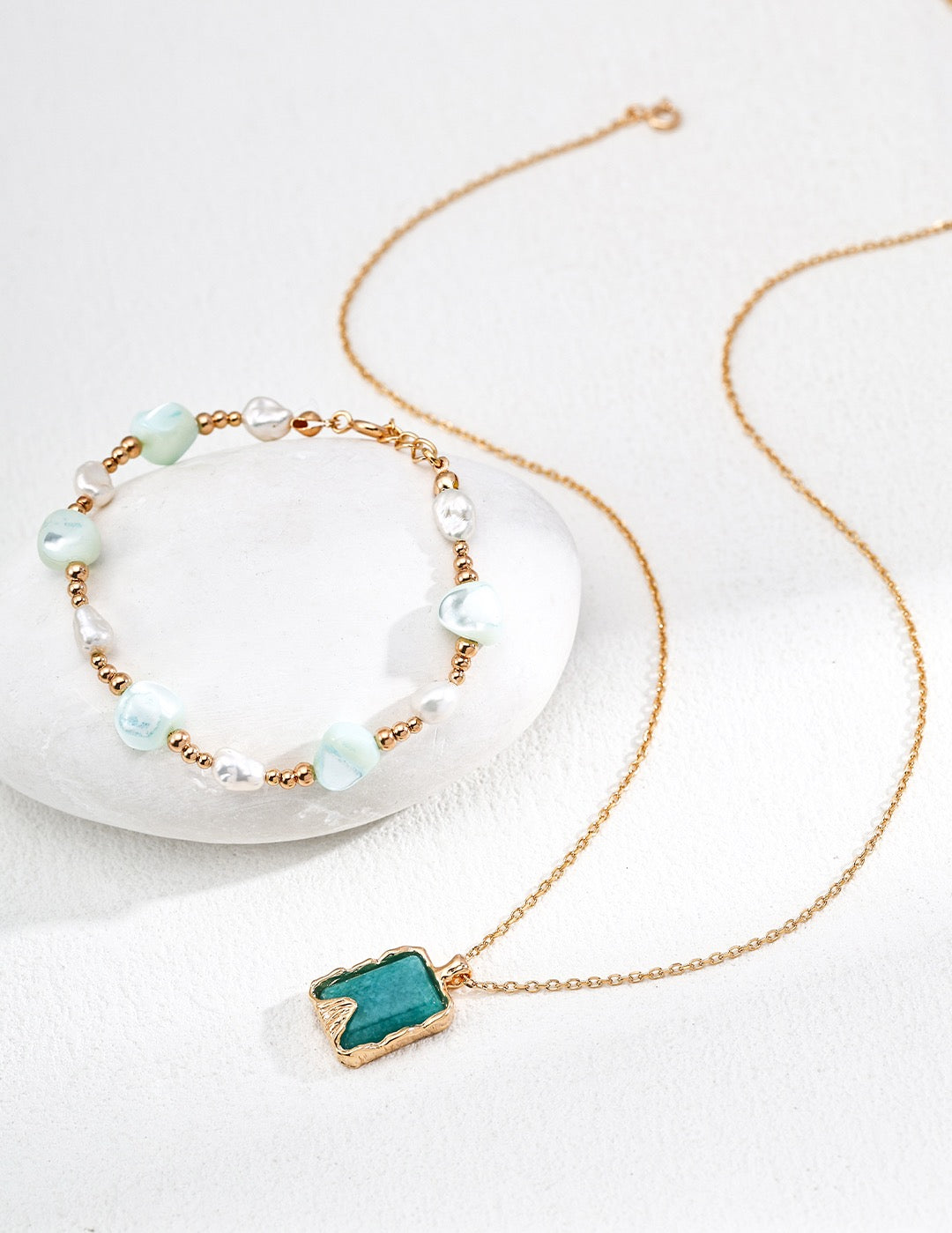 Necklace with a turquoise pendant and bracelet with pearls on a white background