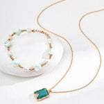 Necklace with a turquoise pendant and bracelet with pearls on a white background