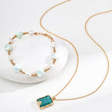 Necklace with a turquoise pendant and bracelet with pearls on a white background
