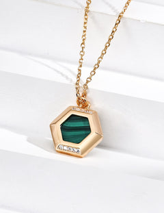 Gold necklace with a green hexagonal pendant on a white background