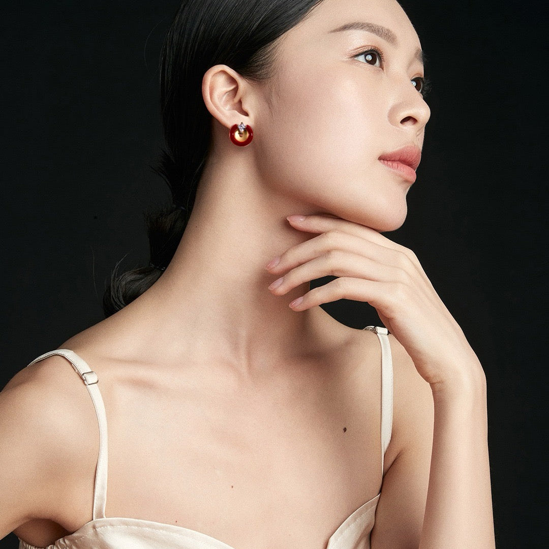 Woman wearing a gold earring against a black background