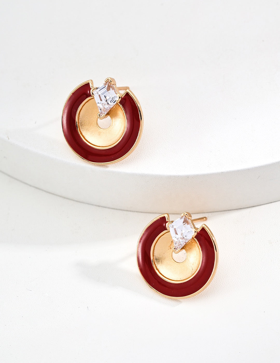 Gold and red earrings with clear gemstones on a white background