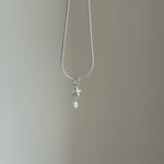 Silver necklace with a star and pearl pendant on a plain background