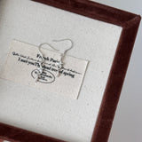 Earring displayed on a card with text in a brown frame