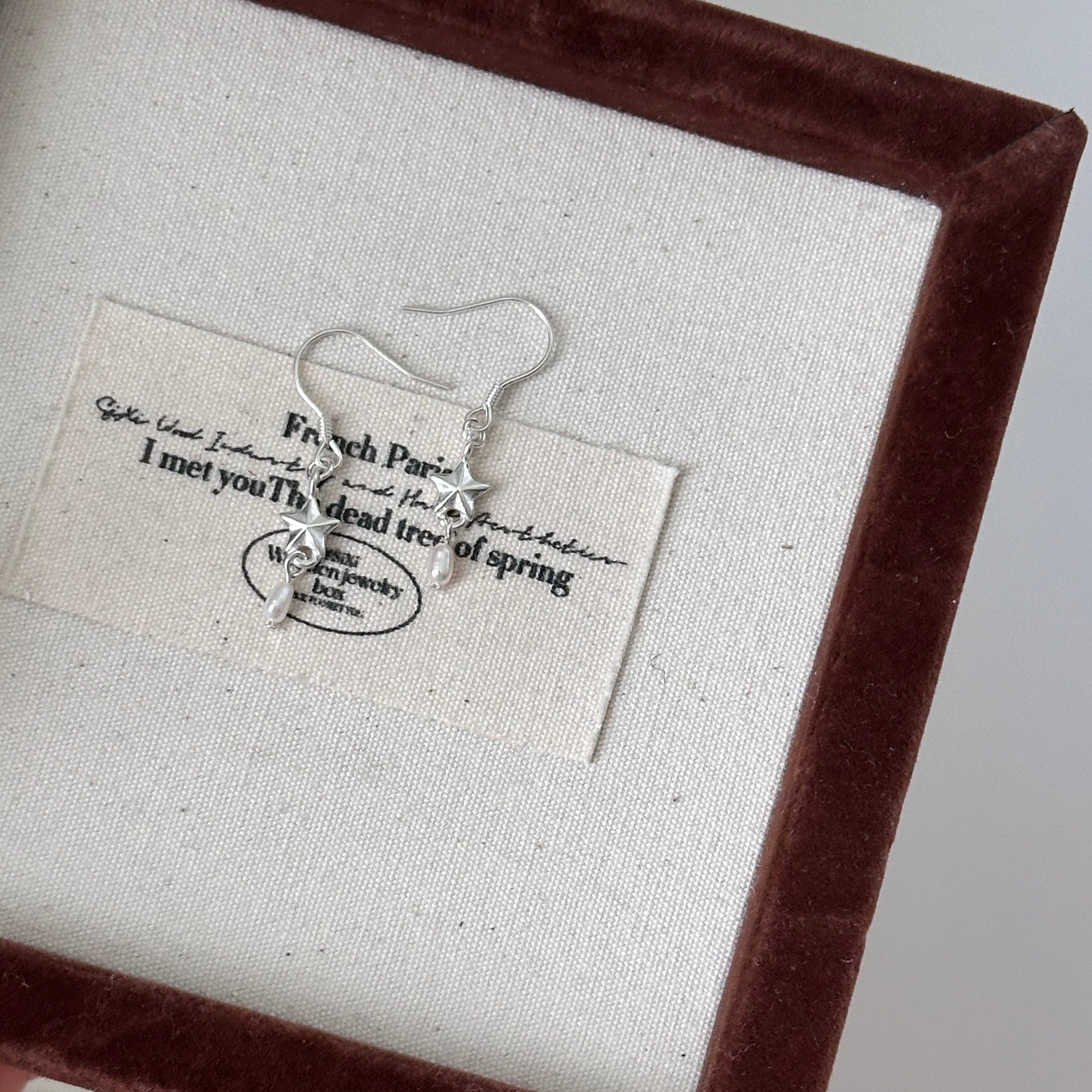 Earring displayed on a card with text in a brown frame