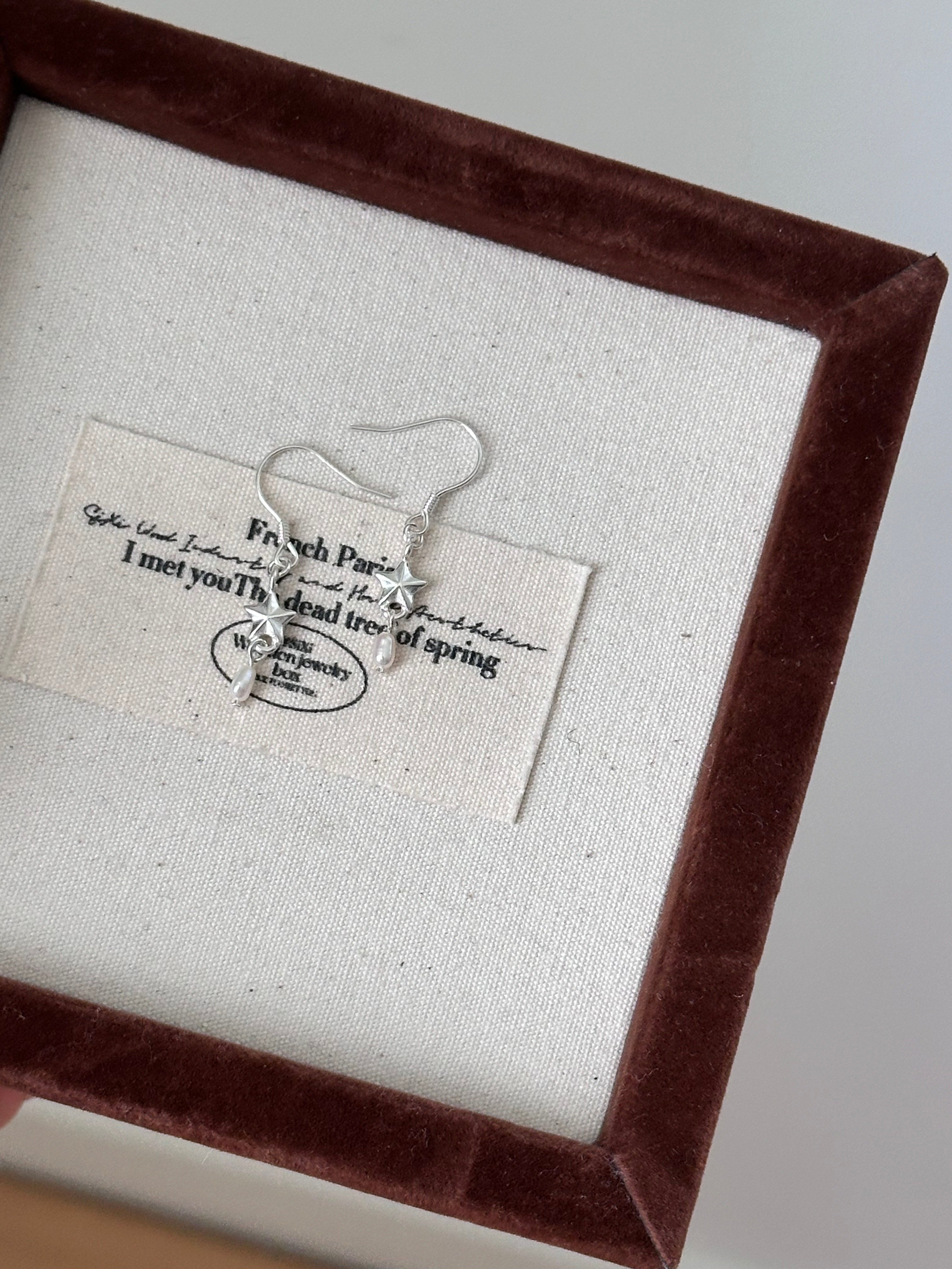 Earring displayed on a card with text in a brown frame