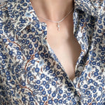 Floral patterned shirt with a deep neckline and necklace.