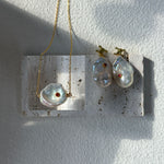 Jewelry display with two pendants on a white background