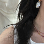 Close-up of a person wearing pearl earrings with a blurred background