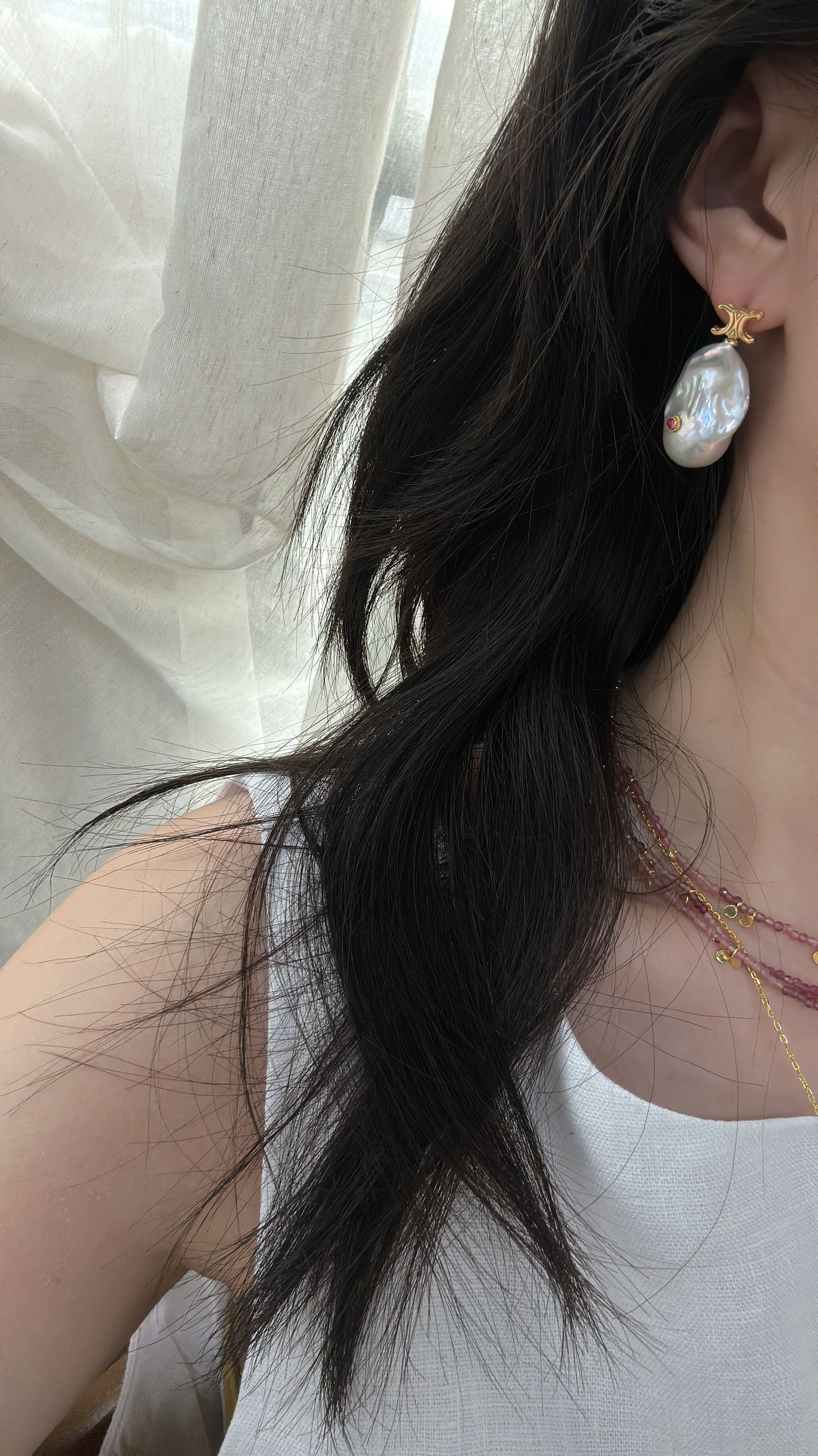 Close-up of a person wearing pearl earrings with a blurred background