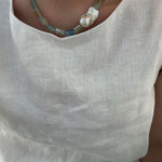 Necklace with a large pearl pendant on a light-colored shirt