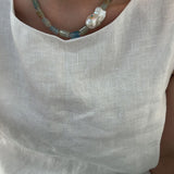 Necklace with a large pearl pendant on a light-colored shirt