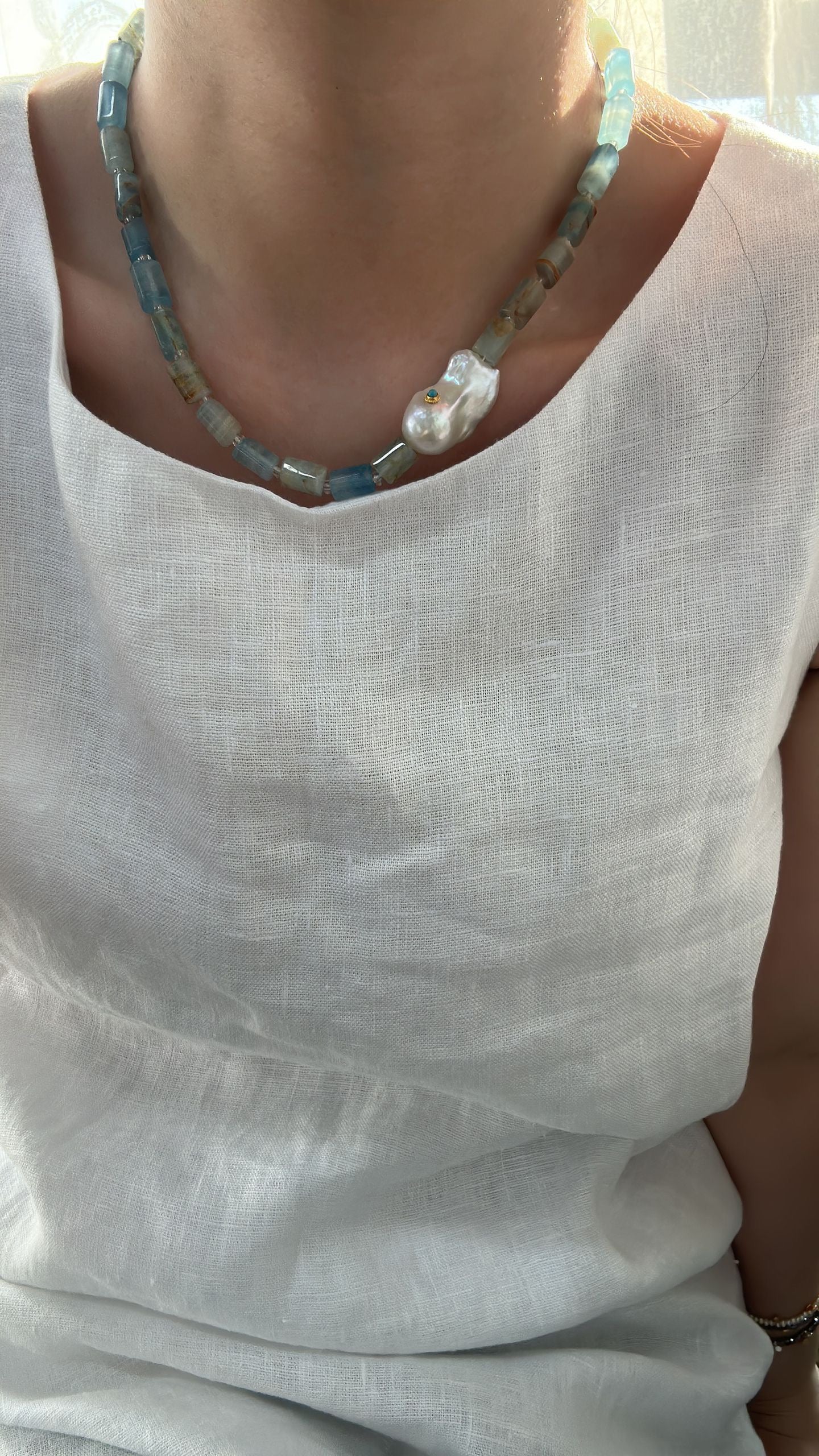 Necklace with a large pearl pendant on a light-colored shirt