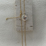 Gold necklace with a pendant on a textured white surface
