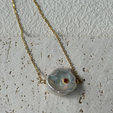 Necklace with a large, irregularly shaped pendant on a textured surface
