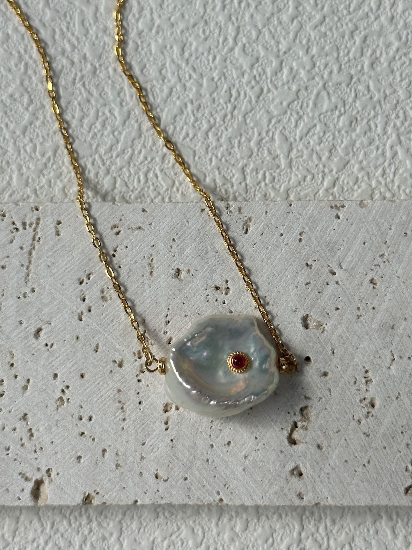 Necklace with a large, irregularly shaped pendant on a textured surface