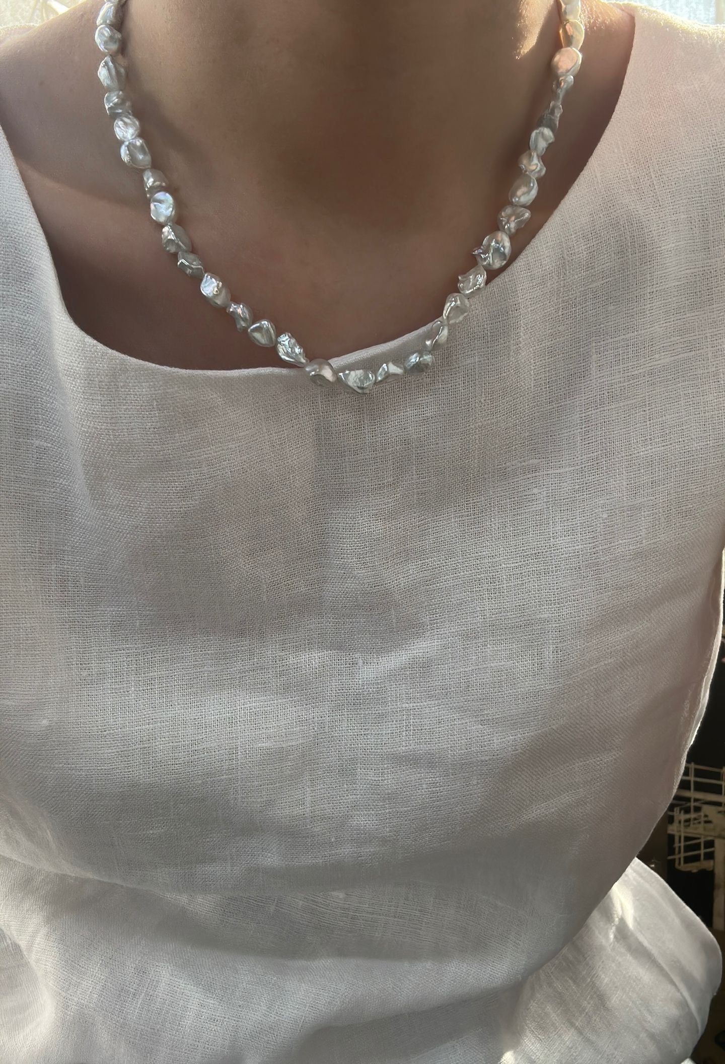 Person wearing a white sleeveless top with a necklace