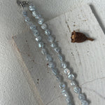 Necklace with blue beads on a textured white surface
