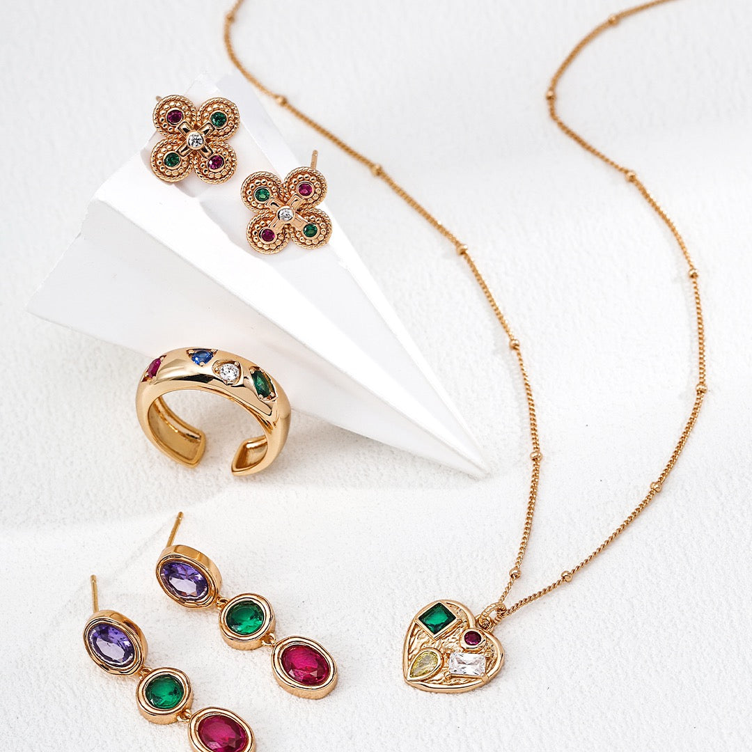Gold jewelry set with colorful gemstones on a white background